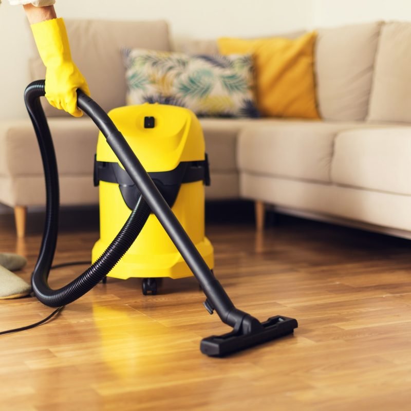 woman cleaning sofa with yellow vacuum cleaner copy space cleaning service concept